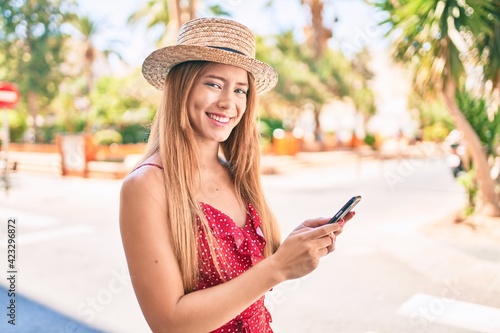 Young caucasian tourist girl smiling happy using smartphone at the city.