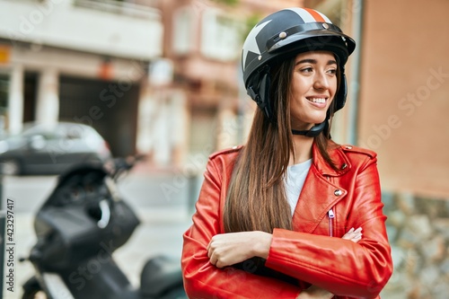 Young hispanic woman smiling happy wearing moto helmet at the city.
