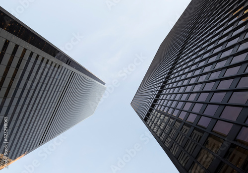 Two office towers appear to be leaning towards one another as they stretch to the sky.
