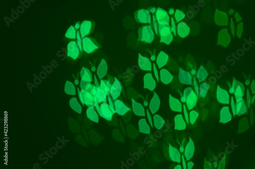 Defocused image of green butterflies on dark green background. Blur background, bokeh.