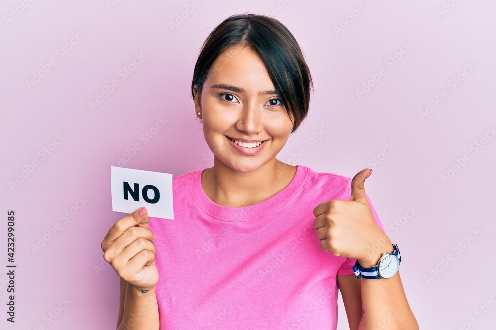 Beautiful young woman with short hair holding no word message smiling happy and positive, thumb up doing excellent and approval sign Beautiful young woman with short hair holding no word message smiling happy and positive, thumb up doing excellent and approval sign