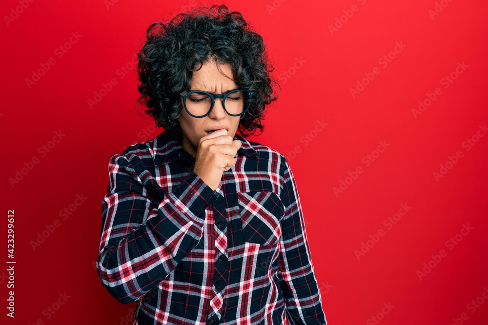 Young hispanic woman with curly hair wearing casual clothes and glasses feeling unwell and coughing as symptom for cold or bronchitis. health care concept.