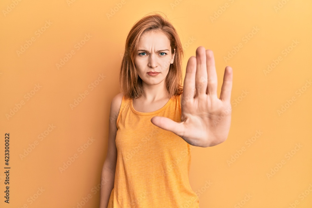 Young caucasian woman wearing casual style with sleeveless shirt doing stop sing with palm of the hand. warning expression with negative and serious gesture on the face. Young caucasian woman wearing casual style with sleeveless shirt doing stop sing with palm of the hand. warning expression with negative and serious gesture on the face.