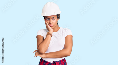 Young african american woman with braids wearing hardhat and builder clothes thinking looking tired and bored with depression problems with crossed arms.