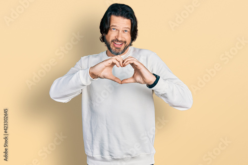 Middle age caucasian man wearing casual clothes smiling in love doing heart symbol shape with hands. romantic concept.