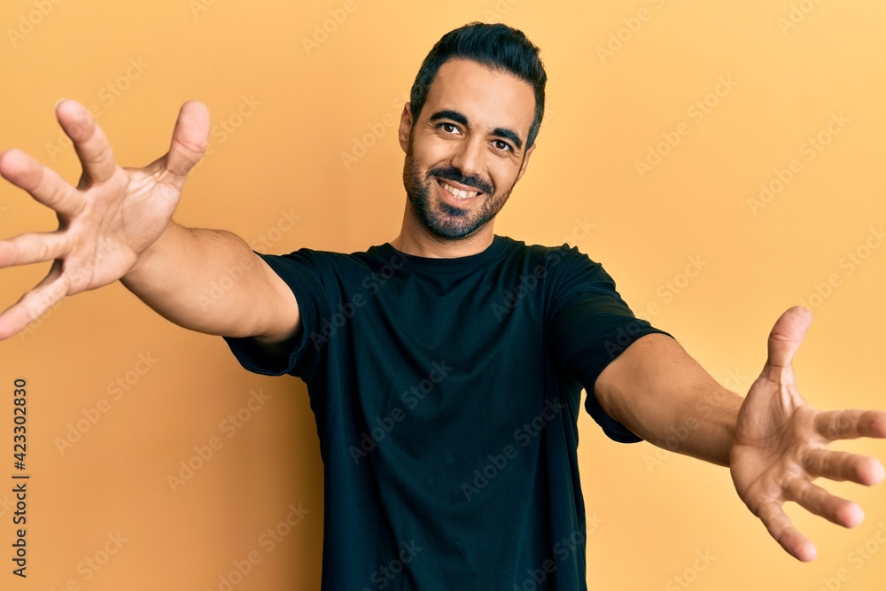 Young hispanic man wearing casual clothes looking at the camera smiling with open arms for hug. cheerful expression embracing happiness. Young hispanic man wearing casual clothes looking at the camera smiling with open arms for hug. cheerful expression embracing happiness.