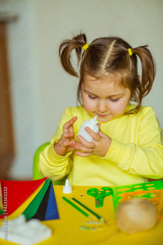 a little beautiful girl makes an application of colored paper a little beautiful girl makes an application of colored paper