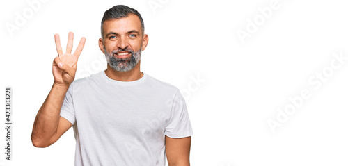 Middle age handsome man wearing casual white tshirt showing and pointing up with fingers number three while smiling confident and happy.