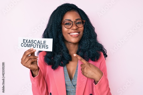 Beautiful african woman holding exascale computers banner smiling happy pointing with hand and finger photo