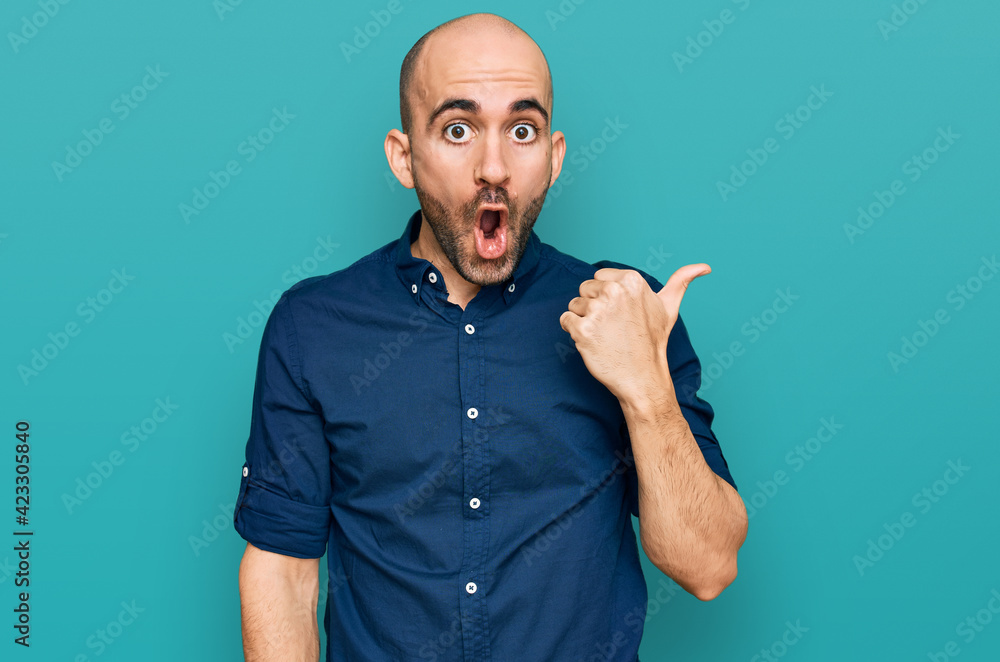 Fototapeta premium Young hispanic man wearing casual clothes surprised pointing with hand finger to the side, open mouth amazed expression.