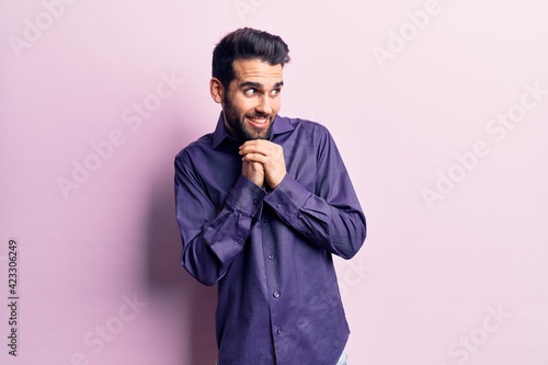 Young handsome man with beard wearing casual shirt laughing nervous and excited with hands on chin looking to the side © Krakenimages.com