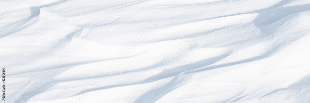 Obraz premium Beautiful winter background with snowy ground. Natural snow texture. Wind sculpted patterns on snow surface. Arctic, Polar region.