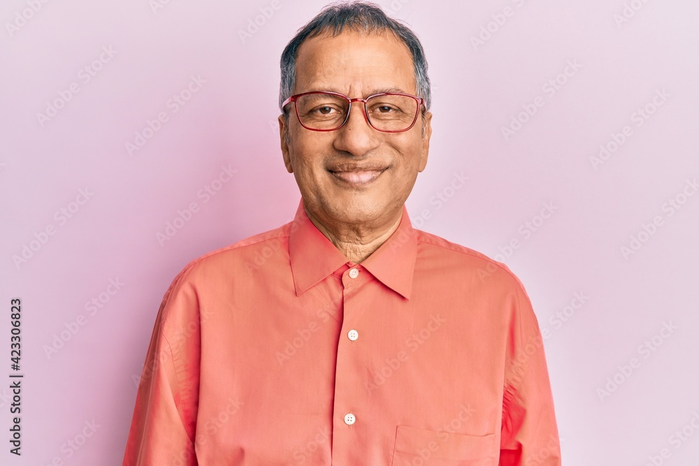 Obraz premium Middle age indian man wearing casual clothes and glasses relaxed with serious expression on face. simple and natural looking at the camera.