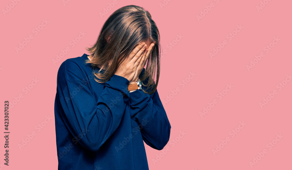 Handsome caucasian man with long hair wearing casual winter sweater with sad expression covering face with hands while crying. depression concept. Handsome caucasian man with long hair wearing casual winter sweater with sad expression covering face with hands while crying. depression concept.
