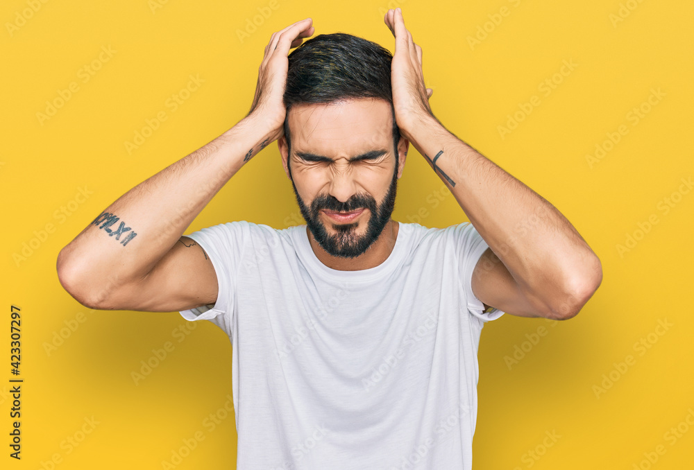 Young hispanic man wearing casual white t shirt suffering from headache desperate and stressed because pain and migraine. hands on head. Young hispanic man wearing casual white t shirt suffering from headache desperate and stressed because pain and migraine. hands on head.