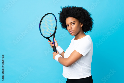 Young African American woman isolated on blue background playing tennis © luismolinero
