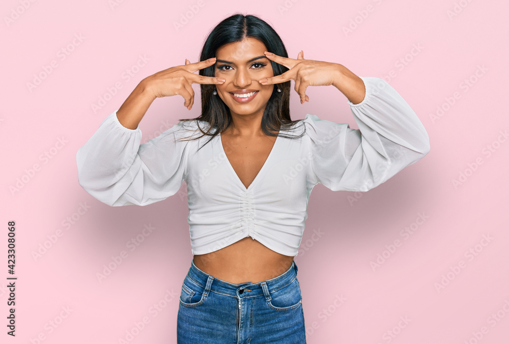 Young latin transsexual transgender woman wearing casual clothes doing peace symbol with fingers over face, smiling cheerful showing victory Young latin transsexual transgender woman wearing casual clothes doing peace symbol with fingers over face, smiling cheerful showing victory