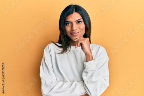 Young latin transsexual transgender woman wearing casual clothes smiling looking confident at the camera with crossed arms and hand on chin. thinking positive.