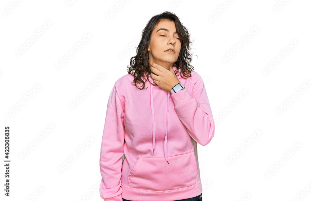 Young hispanic woman wearing casual sweatshirt touching painful neck, sore throat for flu, clod and infection Young hispanic woman wearing casual sweatshirt touching painful neck, sore throat for flu, clod and infection