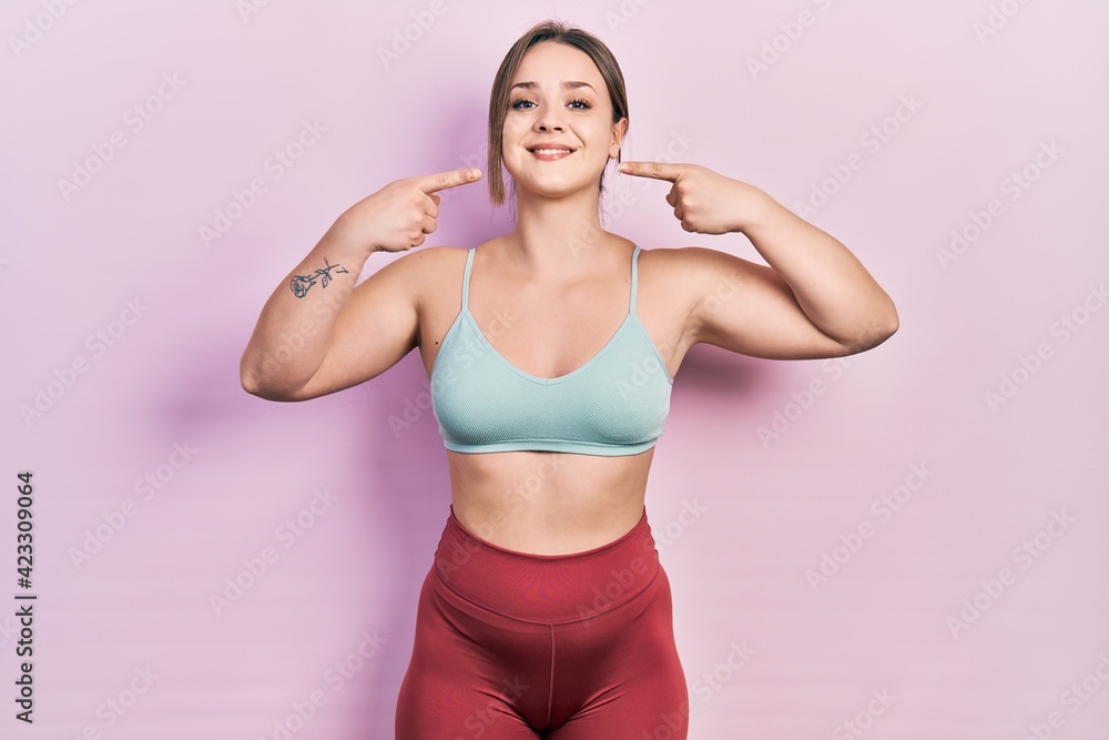 Young hispanic girl wearing sportswear smiling cheerful showing and pointing with fingers teeth and mouth. dental health concept.