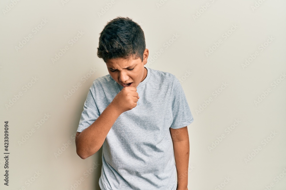 Teenager hispanic boy wearing casual grey t shirt feeling unwell and coughing as symptom for cold or bronchitis. health care concept. Teenager hispanic boy wearing casual grey t shirt feeling unwell and coughing as symptom for cold or bronchitis. health care concept.