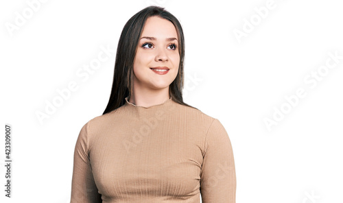 Young hispanic woman wearing casual clothes looking to side, relax profile pose with natural face and confident smile. © Krakenimages.com