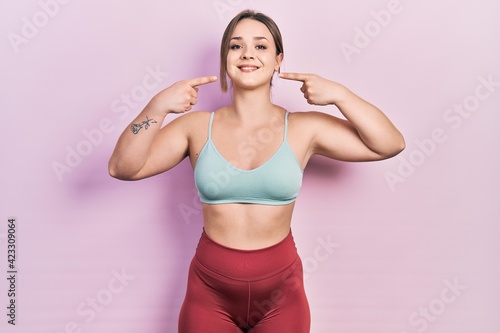 Young hispanic girl wearing sportswear smiling cheerful showing and pointing with fingers teeth and mouth. dental health concept. © Krakenimages.com