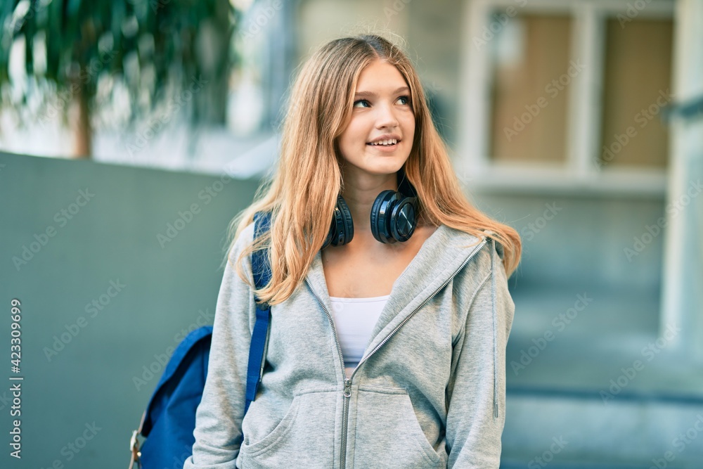 Beautiful caucasian student teenager smiling happy using headphones at the city. Beautiful caucasian student teenager smiling happy using headphones at the city.