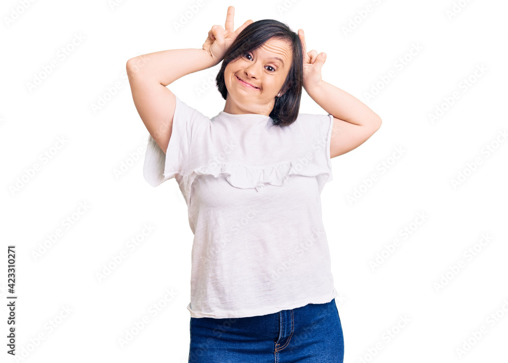 Brunette woman with down syndrome wearing casual white tshirt posing funny and crazy with fingers on head as bunny ears, smiling cheerful Brunette woman with down syndrome wearing casual white tshirt posing funny and crazy with fingers on head as bunny ears, smiling cheerful