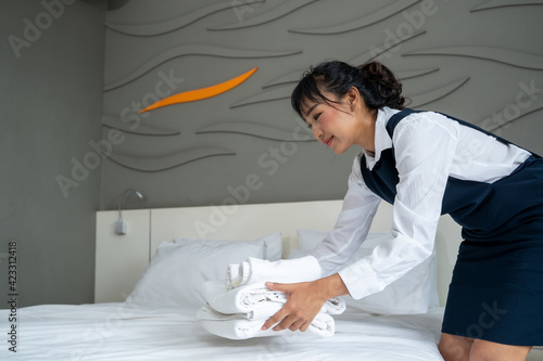 Chambermaid holding stack of fresh towels after cleaning hotel room.
