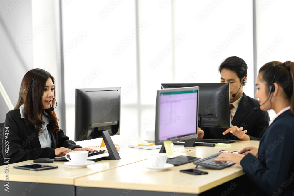Group of happy asian smiling call center business operator customer help support team phone services agen working and talking with headset on desktop computer at call center office