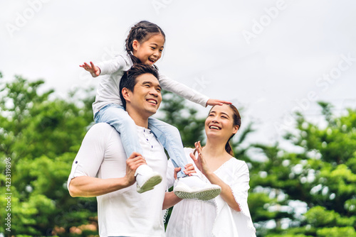 Portrait of enjoy happy love asian family father and mother holding cute little asian girl child smiling playing and having fun moments good time in summer park at home photo