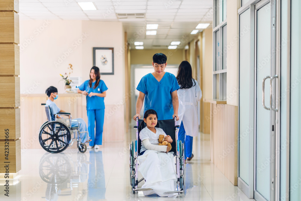 Group of professional medical doctor team with stethoscope in uniform service help support discussing and consulting talk to little girl patient in wheelchair and check up information in hospital Group of professional medical doctor team with stethoscope in uniform service help support discussing and consulting talk to little girl patient in wheelchair and check up information in hospital
