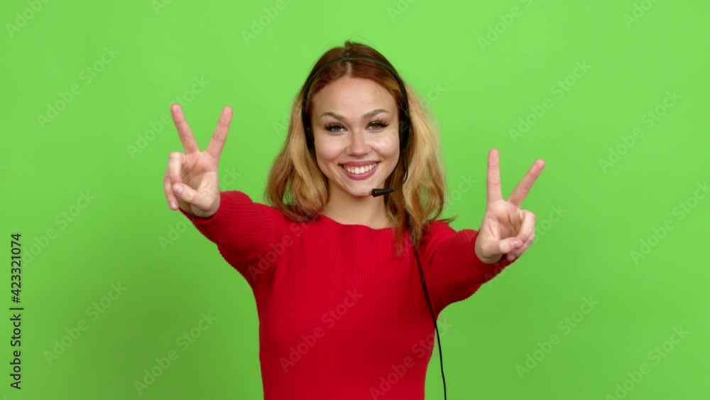 Young blonde teenager girl telemarketer smiling and showing victory sign with a cheerful face over isolated background. Green screen chroma key Young blonde teenager girl telemarketer smiling and showing victory sign with a cheerful face over isolated background. Green screen chroma key