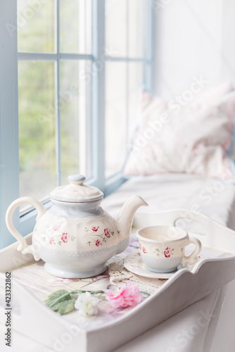 Morning tea near a window. Tea pot and a cup. Tender beautiful blue decor