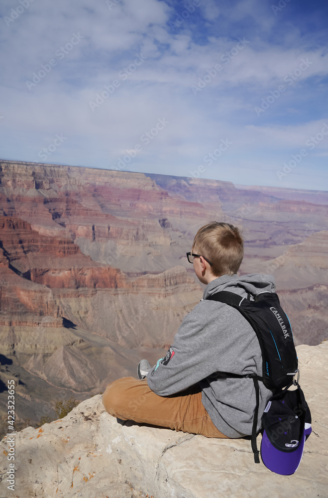 boy sitting very close to edge of grand canyon boy sitting very close to edge of grand canyon