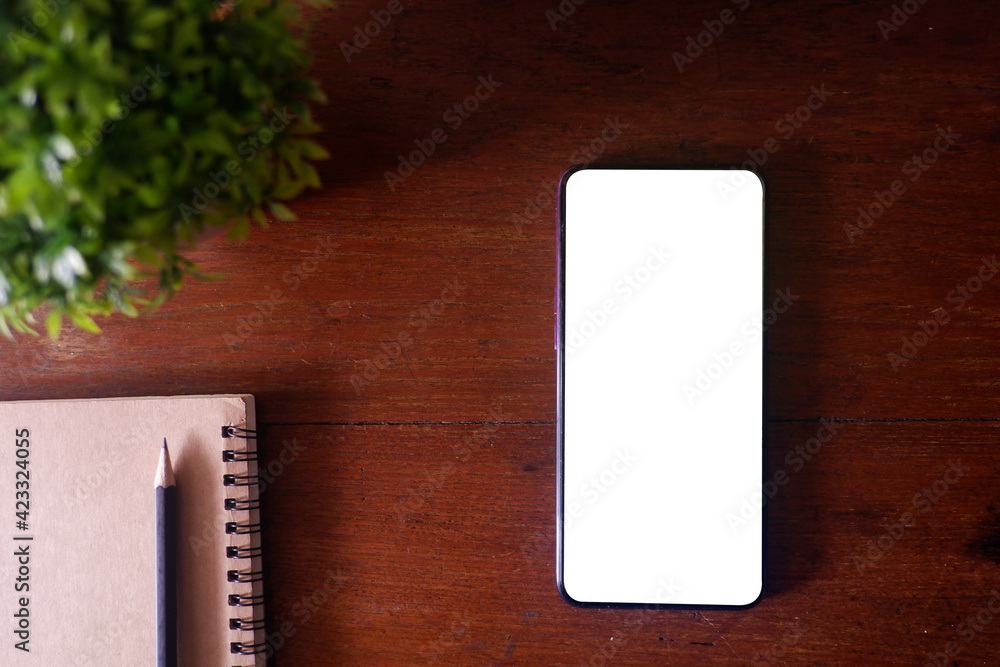 Cropped shot view of wood office desk table with smart phone with white blank screen in modern place. Cropped shot view of wood office desk table with smart phone with white blank screen in modern place.