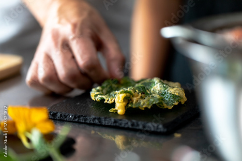 main en train de placer une feuille frite sur une ardoise stylisme culinaire