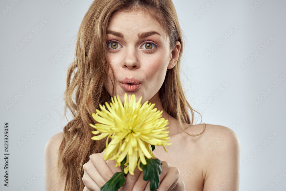 Portrait of a beautiful woman with a yellow flower on a light background cropped with Copy Space Model Portrait of a beautiful woman with a yellow flower on a light background cropped with Copy Space Model