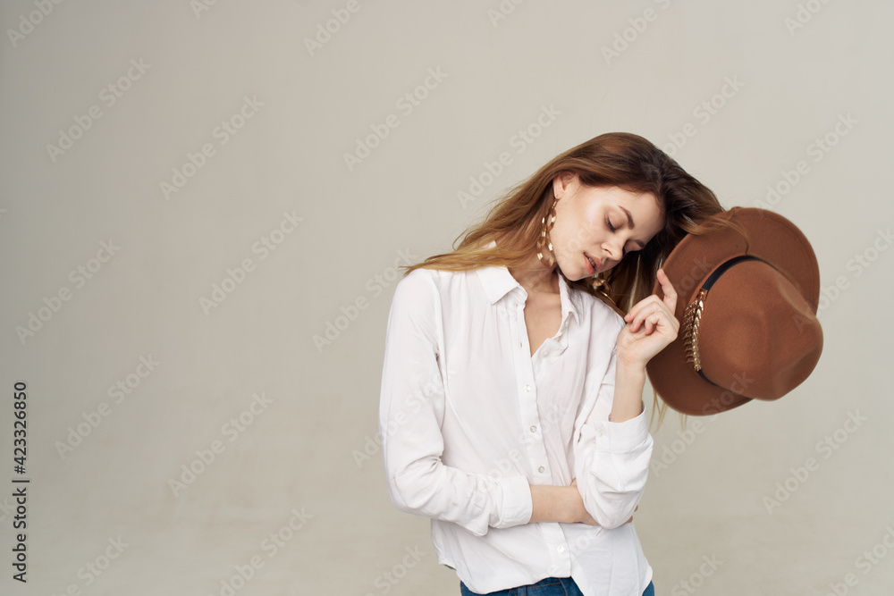 Pretty woman holding hat in her hand white shirt fashion lifestyle beige background Pretty woman holding hat in her hand white shirt fashion lifestyle beige background