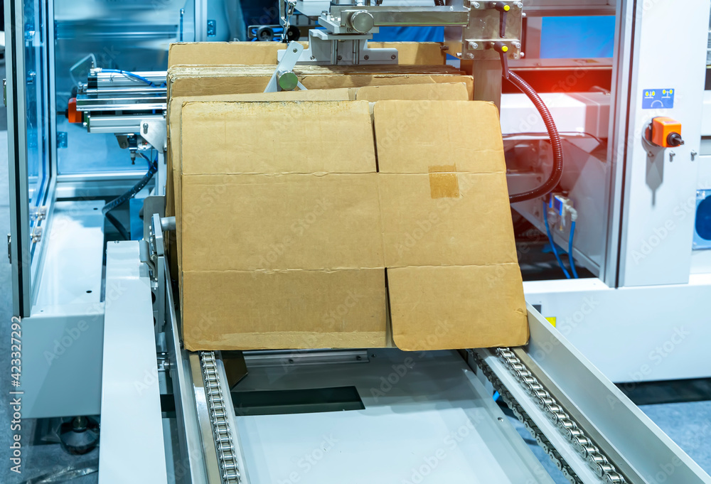 cardboard box of product packaging is moving on conveyor belt of automatic packing  machine in the manufacturing factory Photos | Adobe Stock