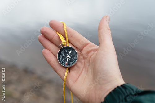 tourist compass lies in the palm of the hand against the background of water. travel planning and path selection.