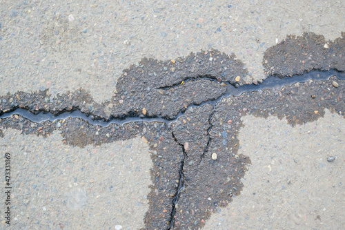 Water flows through cracks in the asphalt. Dry and wet asphalt. The concept of a channel in hard ground.