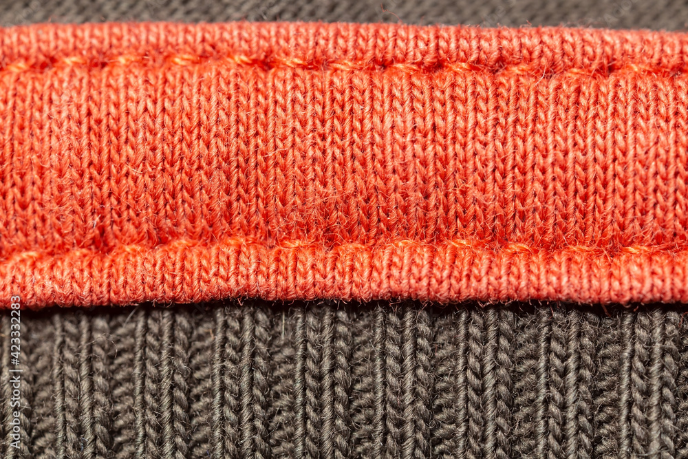 Bright knitted garment with seams, orange and gray. Copy space. Macro. Background.