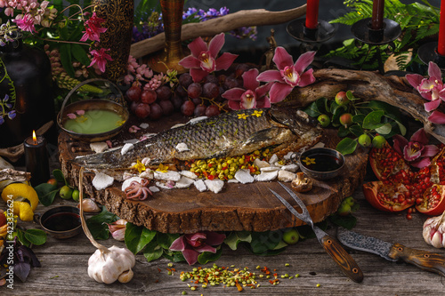 Still life in old masters style with fish, glass of wine, old dishes, fruits. The concept of a richly decorated table.