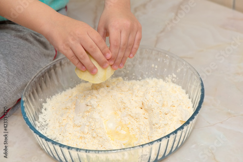 Hands of a child squeezing a lemon on the ingredients of a cake
