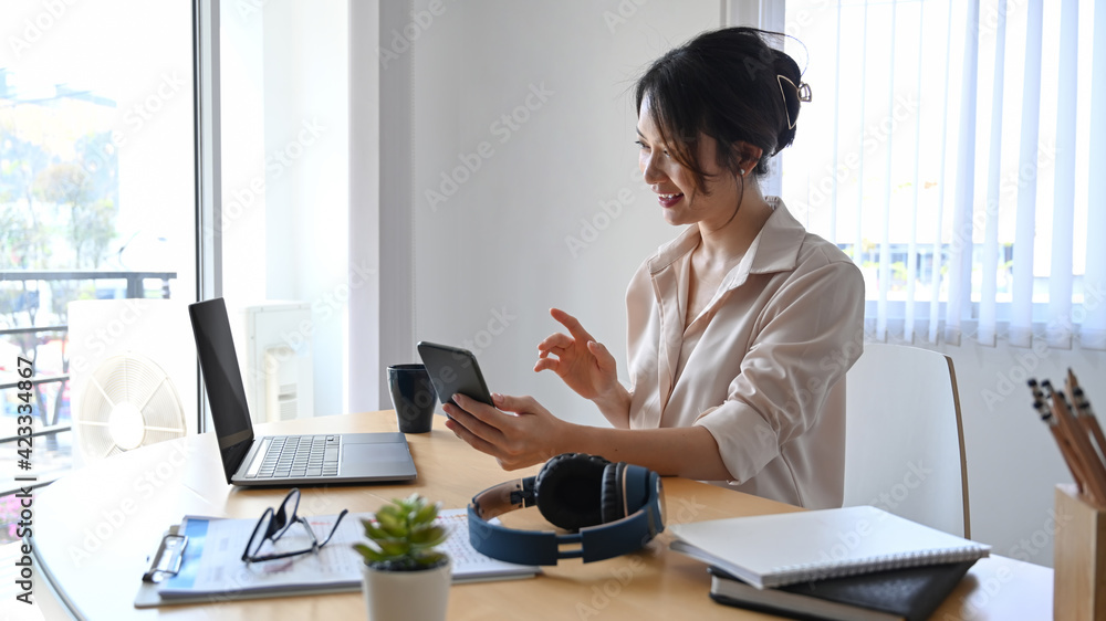 Happy woman accountant working with laptop computer and using smart phone at office. Happy woman accountant working with laptop computer and using smart phone at office.