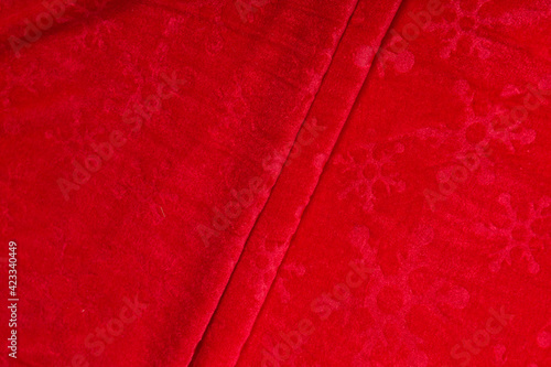 Colored red textile satin fabric folded in folds and waves with highlights and texture