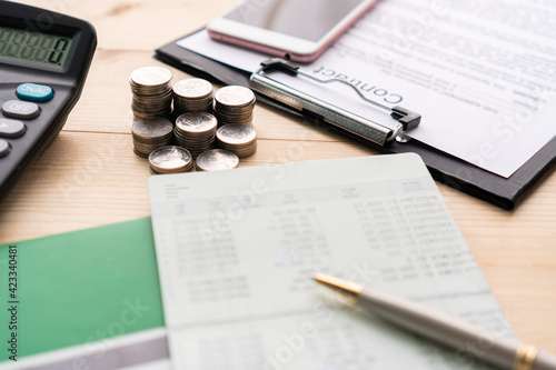 Close up of bank book, money, paper work and calculator on a wooden table. Account, loan, collect money and investments concept. Flat lay