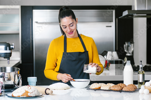 Latin Woman standing in kitchen and kneading dough to bake Conchas traditional Mexican bread